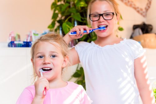 Two sisters in bathroom brushing teeth