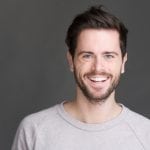 Closeup portrait of a happy young man smiling on gray background