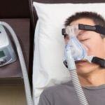 Man with sleep apnea using CPAP machine